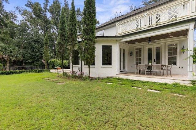 rear view of house with ceiling fan, a yard, and a patio