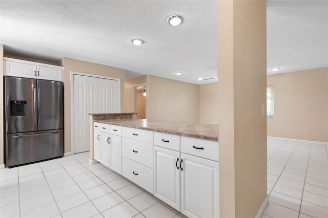 kitchen with white cabinets, light tile patterned floors, a textured ceiling, and stainless steel refrigerator with ice dispenser