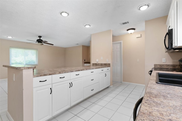 kitchen featuring a textured ceiling, kitchen peninsula, ceiling fan, white cabinets, and light tile patterned flooring