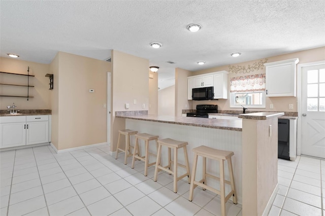 kitchen featuring white cabinetry, sink, black appliances, kitchen peninsula, and a kitchen breakfast bar