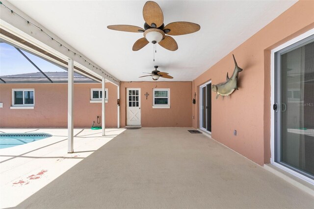 view of patio featuring ceiling fan and glass enclosure