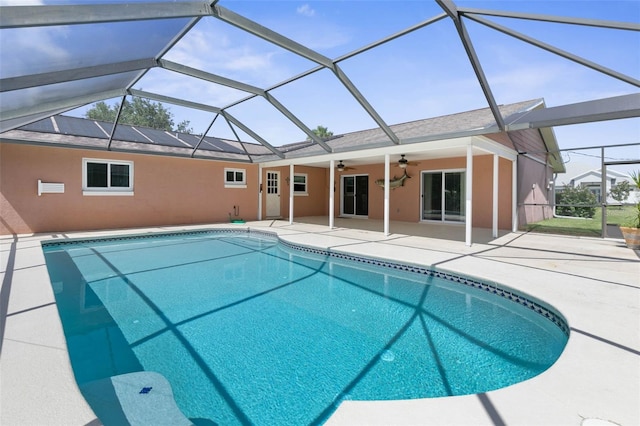 view of swimming pool featuring glass enclosure, ceiling fan, and a patio area