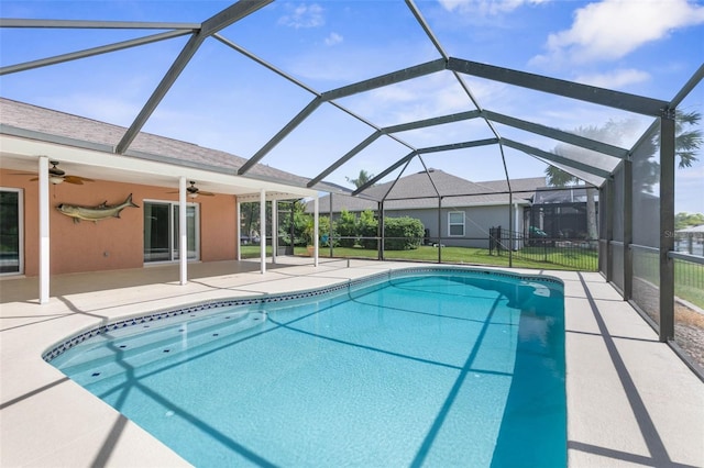 view of swimming pool featuring a yard, ceiling fan, a patio, and glass enclosure