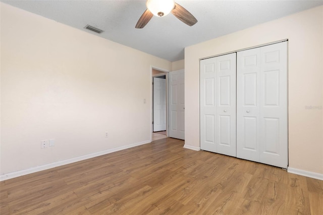 unfurnished bedroom featuring light hardwood / wood-style flooring, ceiling fan, and a closet