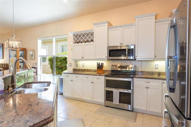 kitchen with pendant lighting, stainless steel appliances, sink, white cabinets, and light tile patterned flooring