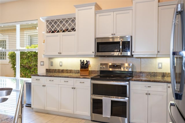 kitchen featuring white cabinets, dark stone countertops, stainless steel appliances, and backsplash