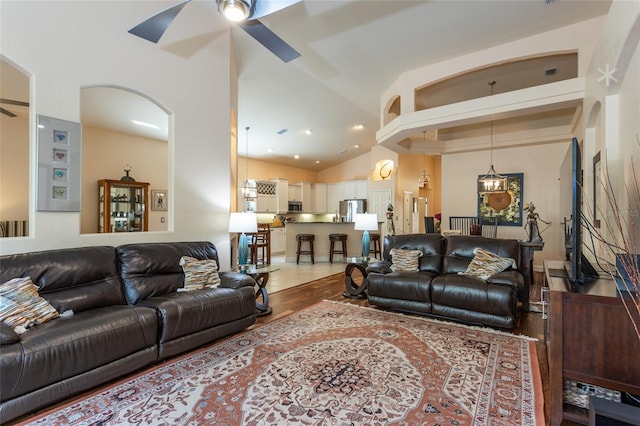 living room with light hardwood / wood-style flooring, ceiling fan, and high vaulted ceiling