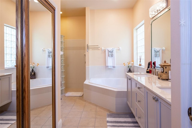 bathroom featuring tile patterned flooring, plenty of natural light, a relaxing tiled tub, and vanity