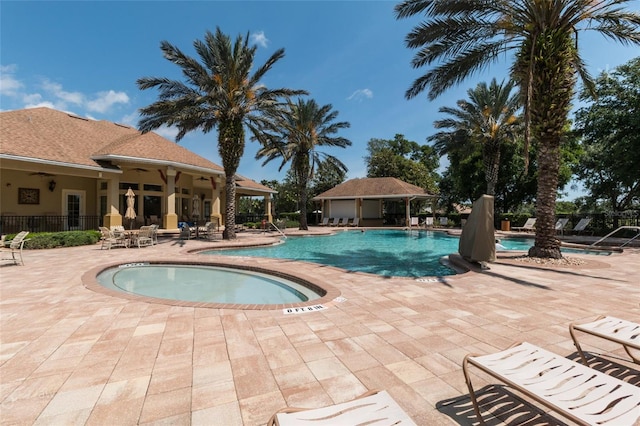 view of swimming pool featuring a hot tub and a patio