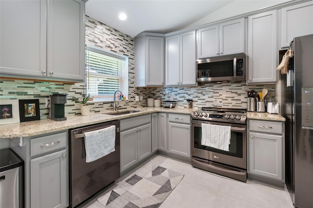 kitchen with light tile patterned floors, decorative backsplash, appliances with stainless steel finishes, gray cabinetry, and a sink