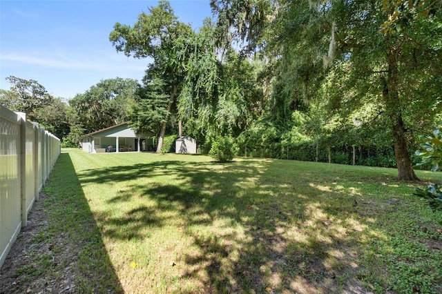 view of yard with a shed, fence, and an outdoor structure