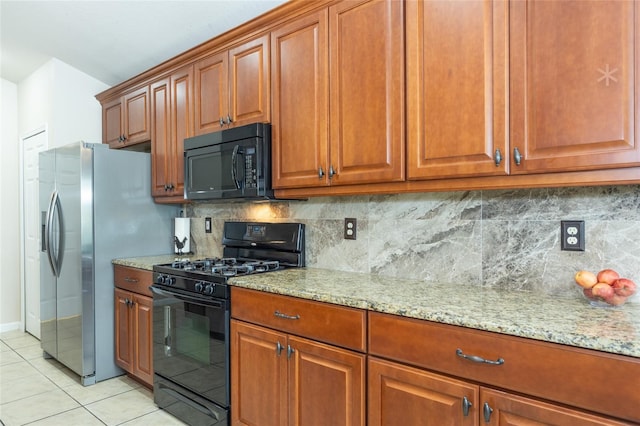 kitchen featuring black appliances, light stone countertops, light tile patterned floors, and decorative backsplash