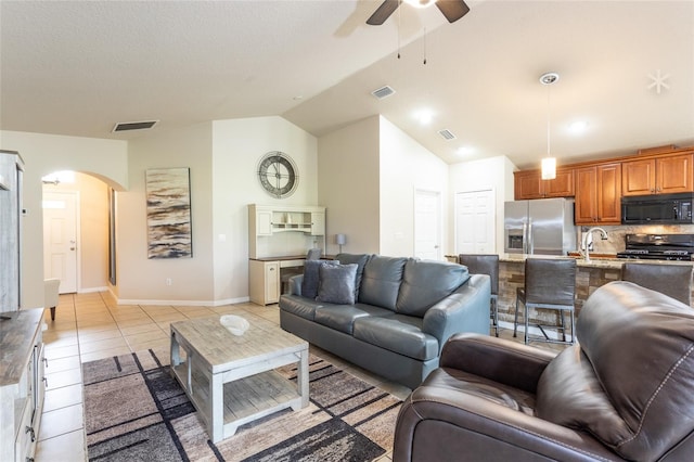 living room featuring lofted ceiling, ceiling fan, sink, and light tile patterned floors