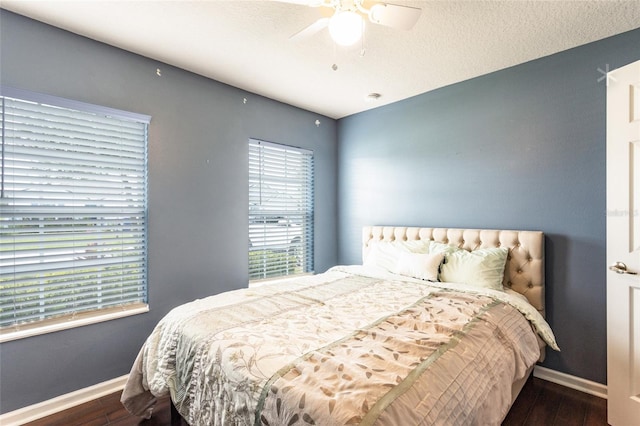 bedroom with multiple windows, ceiling fan, dark hardwood / wood-style floors, and a textured ceiling