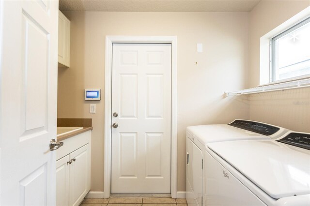 laundry area featuring light tile patterned floors, cabinets, and washer and dryer