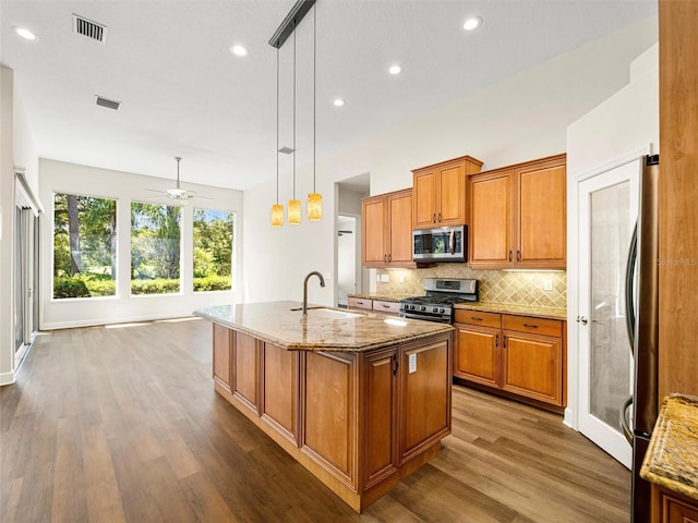 kitchen with dark hardwood / wood-style floors, an island with sink, stainless steel appliances, sink, and ceiling fan