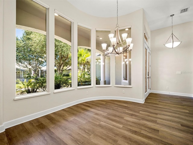 unfurnished room with a chandelier and dark hardwood / wood-style floors