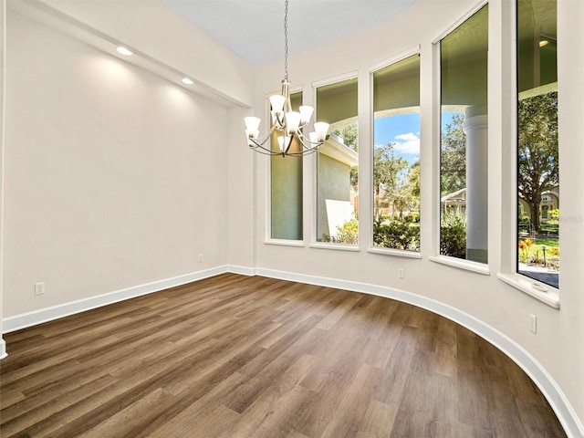 unfurnished room featuring wood-type flooring and an inviting chandelier