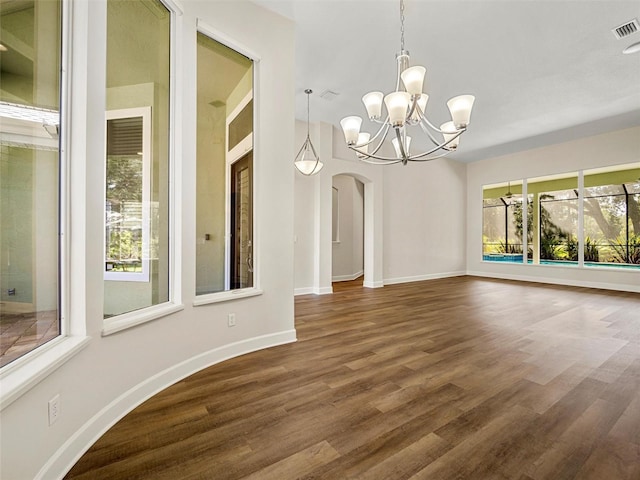 unfurnished dining area with wood-type flooring, plenty of natural light, and an inviting chandelier