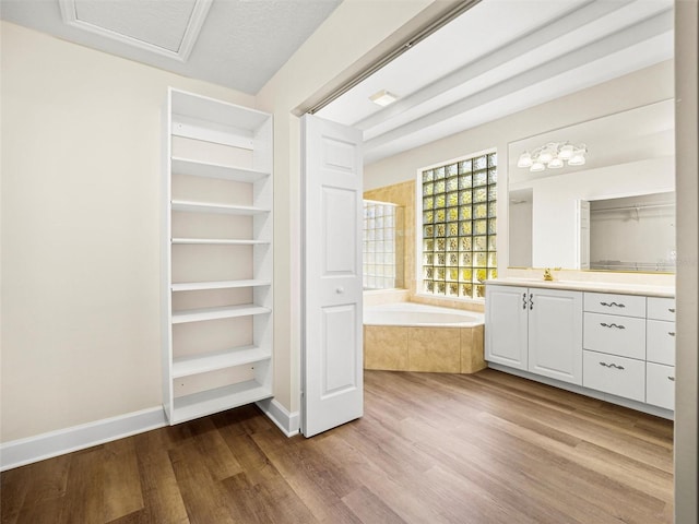 bathroom with vanity, a textured ceiling, hardwood / wood-style flooring, and tiled bath