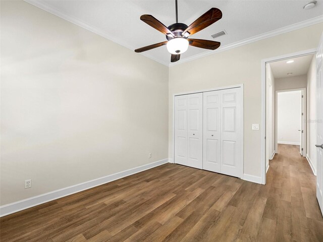 unfurnished bedroom with crown molding, wood-type flooring, ceiling fan, and a closet