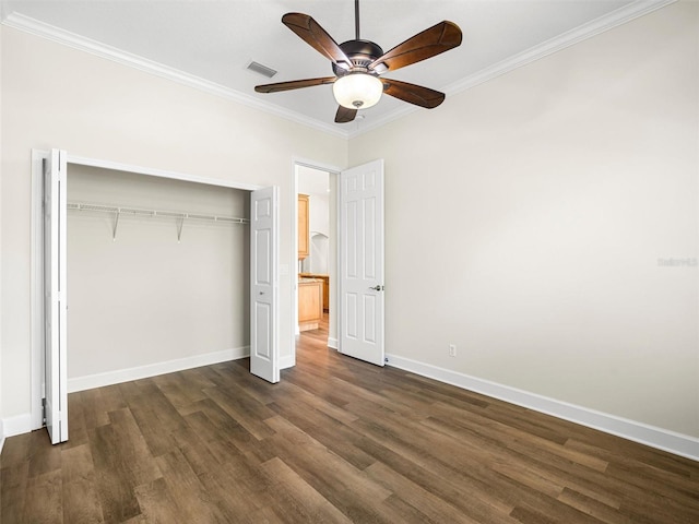 unfurnished bedroom with crown molding, dark hardwood / wood-style flooring, ceiling fan, and a closet