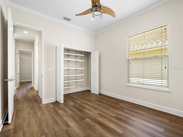 unfurnished bedroom with ornamental molding, ceiling fan, dark hardwood / wood-style floors, and a closet