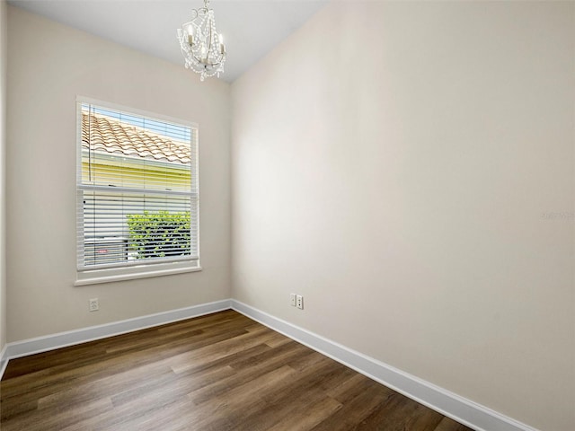 unfurnished room with an inviting chandelier and wood-type flooring