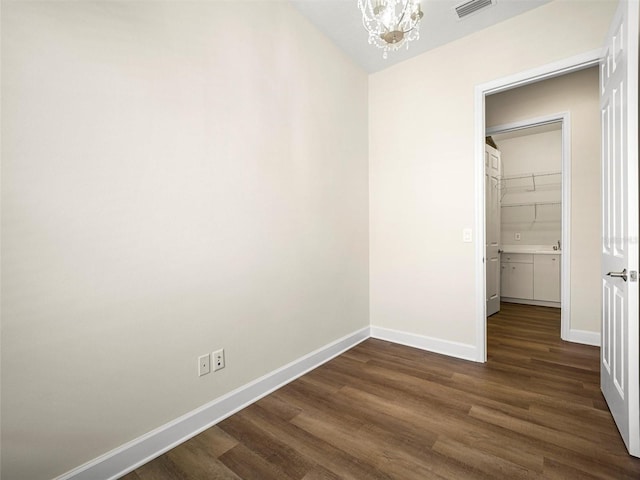 unfurnished bedroom with dark wood-type flooring, a notable chandelier, and a closet