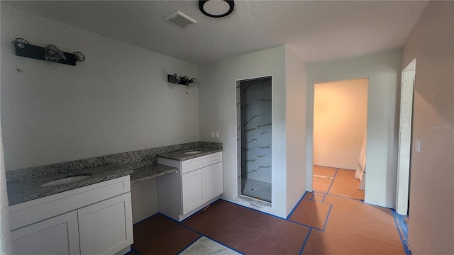 bathroom with tile patterned flooring, vanity, a textured ceiling, and walk in shower