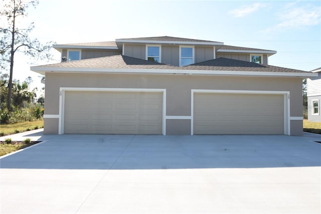 view of front facade featuring an attached garage, a shingled roof, and stucco siding