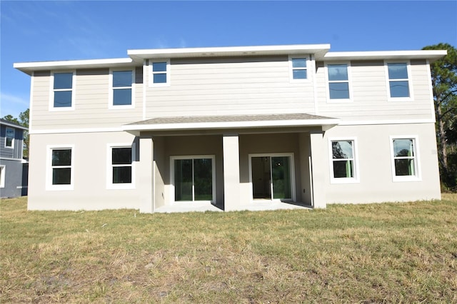 back of property featuring a yard and stucco siding