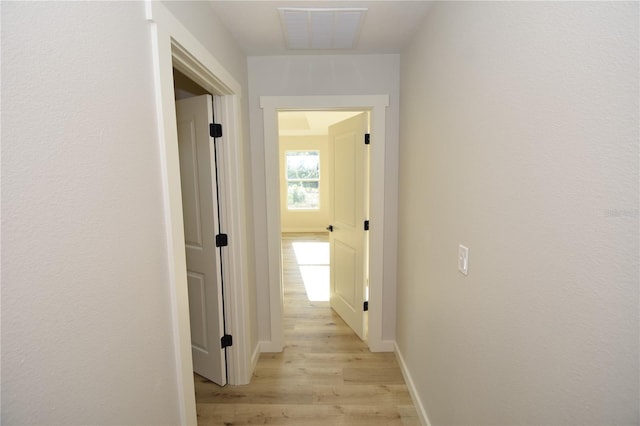 hall featuring visible vents, light wood-style flooring, and baseboards