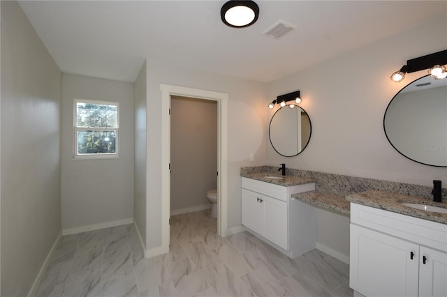 full bath featuring visible vents, two vanities, a sink, and toilet