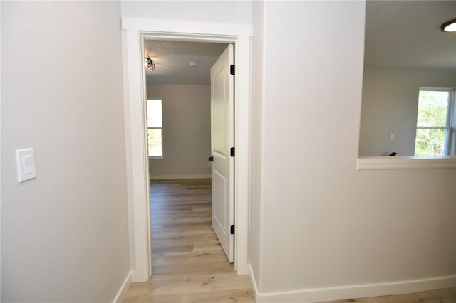 hallway featuring light wood finished floors and baseboards