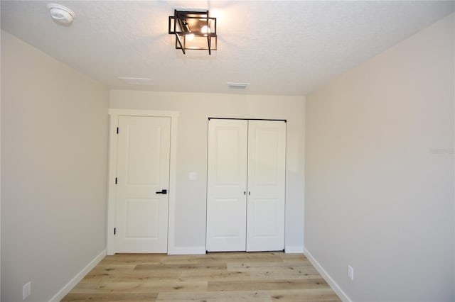 unfurnished bedroom with baseboards, a textured ceiling, visible vents, and light wood-style floors