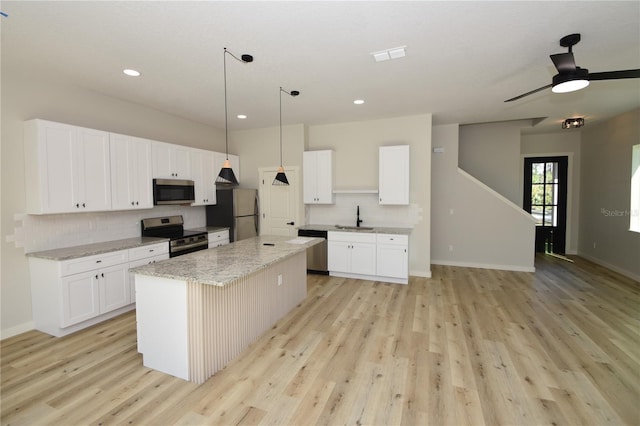 kitchen with pendant lighting, appliances with stainless steel finishes, white cabinets, and a center island