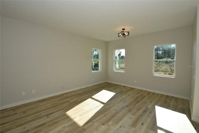 empty room with baseboards, light wood finished floors, and a healthy amount of sunlight