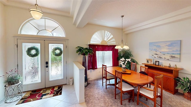 tiled foyer with a textured ceiling, a chandelier, beamed ceiling, and french doors