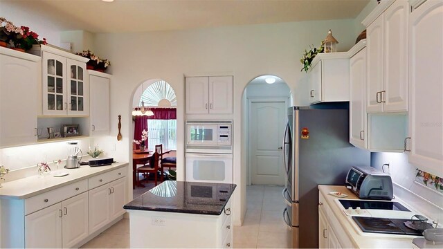 kitchen featuring a kitchen island, white appliances, white cabinets, and light tile patterned flooring