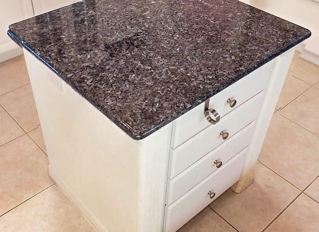 details with dark stone countertops and light tile patterned floors