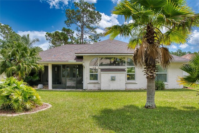 rear view of house featuring a yard and a sunroom