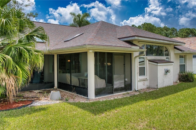 rear view of property with a lawn and a sunroom