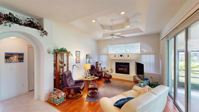 tiled living room featuring ceiling fan and a tray ceiling