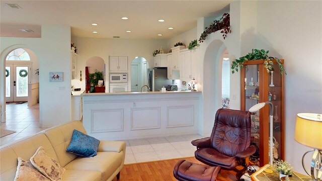 kitchen with french doors, light hardwood / wood-style flooring, white appliances, white cabinetry, and sink