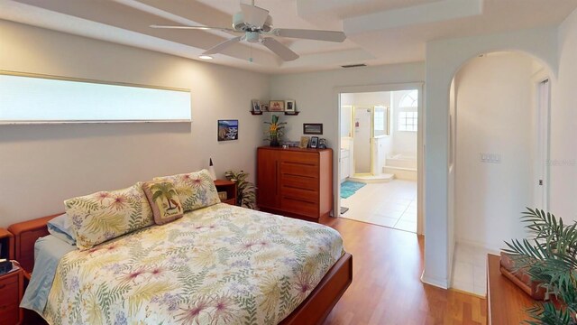 bedroom with multiple windows, ceiling fan, hardwood / wood-style flooring, and connected bathroom