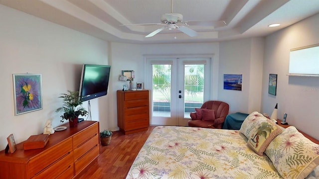 bedroom featuring hardwood / wood-style flooring, french doors, a raised ceiling, access to outside, and ceiling fan