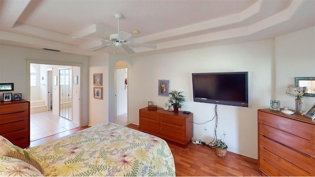 bedroom with a tray ceiling, ceiling fan, and light hardwood / wood-style floors