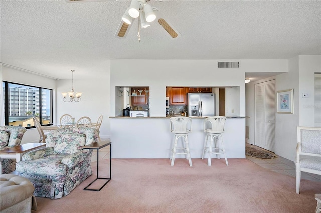 living room with ceiling fan with notable chandelier, a textured ceiling, and light colored carpet