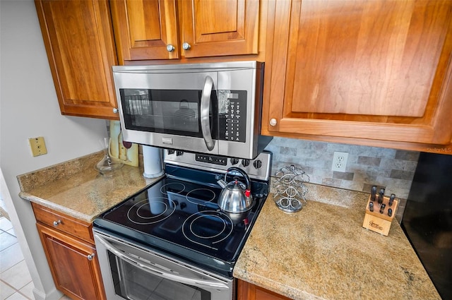 kitchen featuring light stone counters, light tile patterned floors, appliances with stainless steel finishes, and decorative backsplash